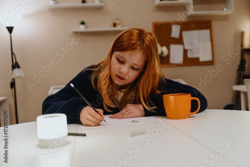 A teenage girl studies in the living room during evening hours, drinking coffee while focusing on homework. Captures authentic student life and modern study routines