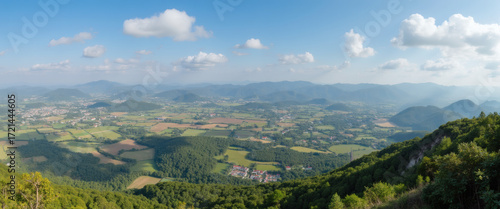 Expansive Panoramic View of Lush Green Valleys and Distant Mountain Ranges Under a Bright Blue Sky with Scattered Clouds, Showcasing Rural Villages and Patchwork Farmlands from an Elevated Perspective