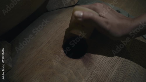 Worker screwing off the cap to open the wine barrel at the beverage production facility. Opening the wooden barrel full of alcoholic wine. Opening the barrel with fresh wine drink at the vinery.