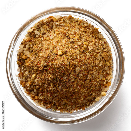 Top view of a glass bowl filled with mixed spices and seasoning blend. Aromatic ground herbs, salt, and powdered spices for cooking, grilling, barbecue, and gourmet recipes.