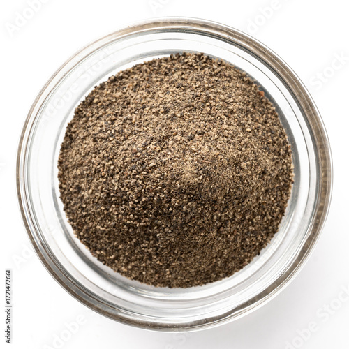 High-resolution closeup photo of ground black pepper in a transparent glass bowl on a white background, top view.