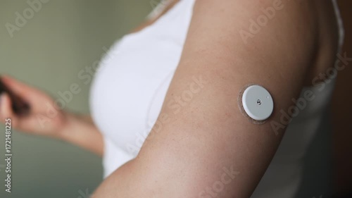 Woman monitors blood sugar levels using smartphone sensor on arm. Morning health checkup ritual for people with diabetes. Technologies that simplify, make life easier for those with chronic disease.