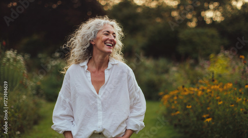 Elderly woman smiling while walking in garden during sunset  