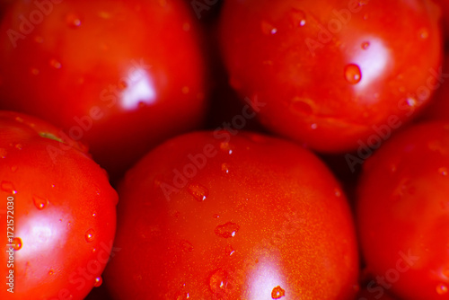 Fresh red tomatoes covered in water droplets on a wooden table