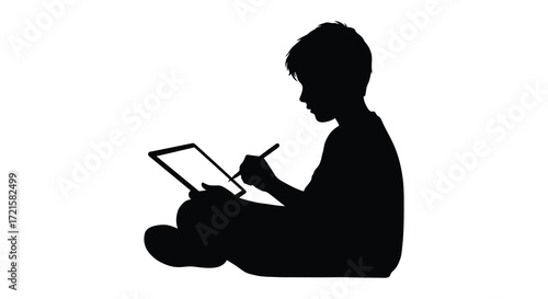 Silhouette of a young boy seated and writing in a notebook