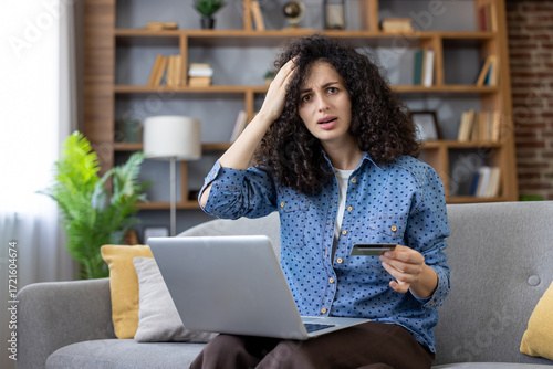Slika na platnu Young woman is having a payment issue while online shopping, holding a credit ca