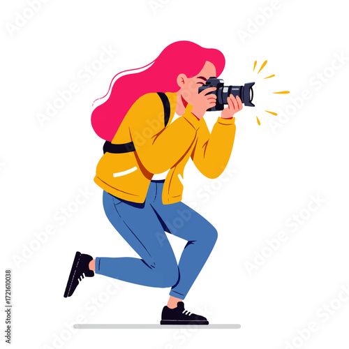 A woman with pink hair kneels while taking a photograph with a digital camera, wearing a yellow jacket and blue jeans.