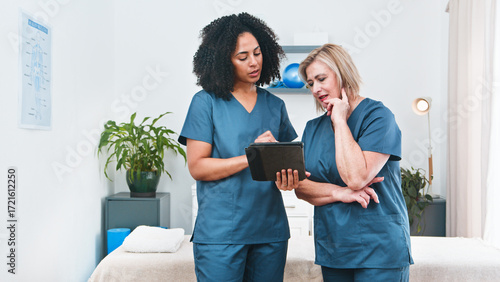 Physiotherapists Review Treatment Plan With Tablet In Clinic Setting During Consultation