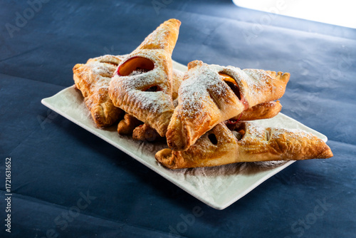 Puff pastry triangles with plum and cinnamon filling. Baked goods. Dessert. Food concept.