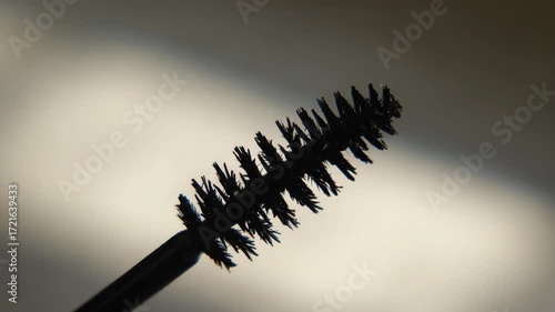 A black mascara brush with a black handle. The brush is long and has a black and brown color