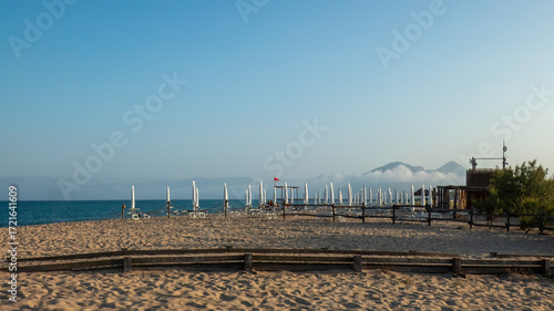 Beach of Marina di Orosei at sunset in the background the closed umbrellas of a bathing establishment - Orosei - Nuoro - Sardinia - Italy