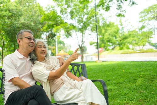 Happy Asian Senior Couple Relaxing Together in Park with Wheelchair