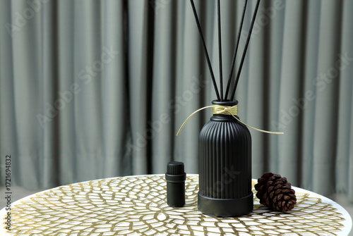 luxury aroma scent reed diffuser glass bottle is on white marble table with essential oil bottle and pine cone to creat romantic and relax ambient with background of nice grey curtain in cozy bedroom