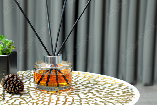 luxury aroma scent reed diffuser glass bottle is on white marble table with essential oil bottle and pine cone to creat romantic and relax ambient with background of nice grey curtain in cozy bedroom