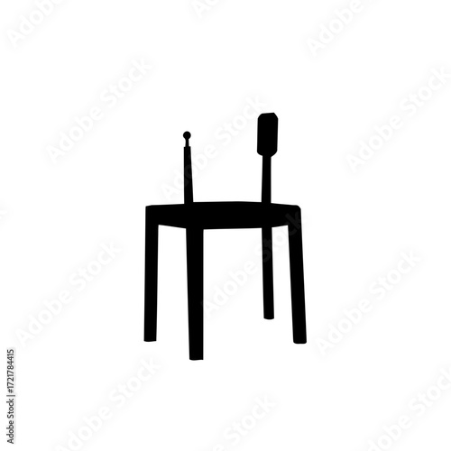 An isolated old black wooden chair with a white plug adapter