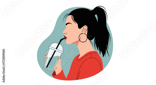 A stylish woman in a red top enjoys a refreshing drink from a transparent cup with a straw.