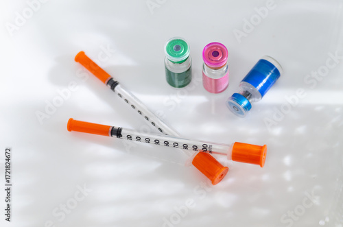 Close up of Vials with Various Injectable Compounds Next to Syringes