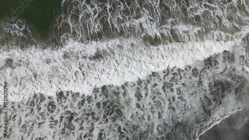 Slow motion waves hitting the shore from directly above along the pacific coast in California, from a drone in 4k. 