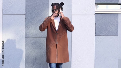 Confident young african american man talking on the phone and smoking an electronic cigarette