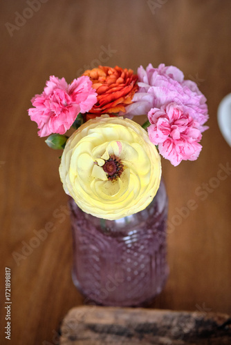 Beautiful bouquet of spring flowers in a vase on the table. Lovely bunch of flowers. Yellow and red buttercups, pink carnations