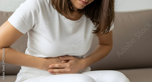 Woman experiencing stomach ache holding her abdomen feeling unwell discomfort pain health medical healthcare illness disease symptom