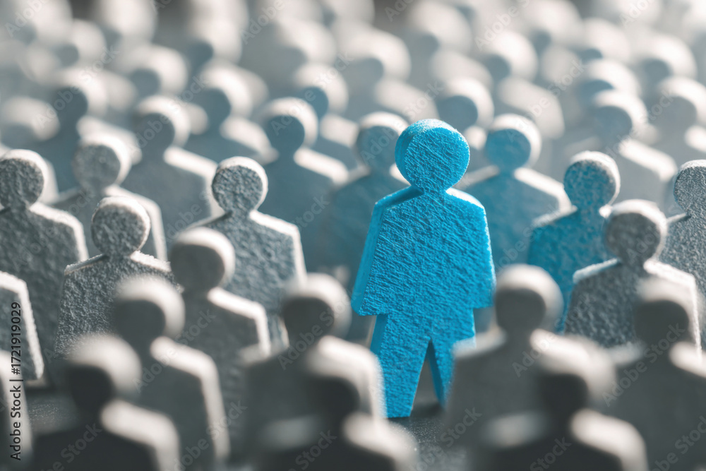 Obraz premium Many gray figures surround a single blue figure, symbolizing individuality in a crowd during a thoughtful moment in a quiet setting