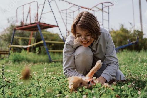 A young woman walks her playful puppy in a sunny garden, sharing a tender moment of love and care. Authentic, unaltered photography capturing the special bond between human and pet