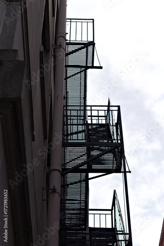 Urban fire escape staircase on the side of a building, showcasing metal structure and architectural detail with a gritty city safety aesthetic.