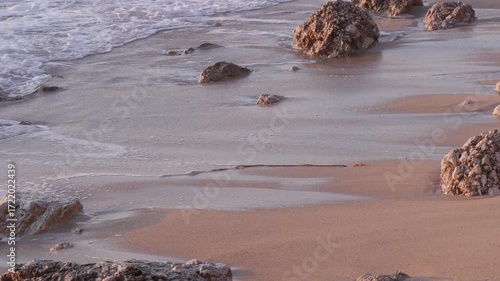 Foamy Waves Crashing Against Coastal Rocks at Sunset on a Slightly Rough Sea