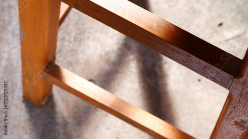 Wooden chair with sunlight reflect on texture with blurred cement floor. Top view of chair legs. Concept of summer, wood, interior, warm, light, shadow for poster, print, abstract wallpaper.