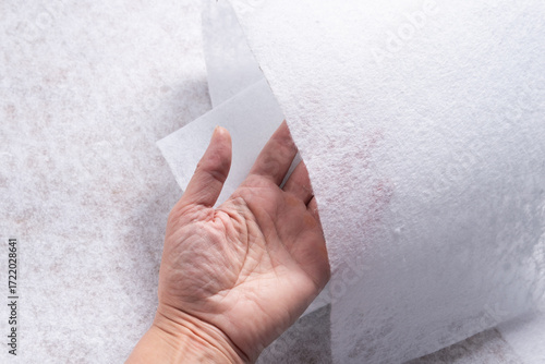 Hand Holding White Geotextile Fabric Sheet with Visible Texture, Close-Up