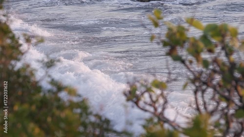 Foamy Waves Crashing Against Coastal Rocks at Sunset on a Slightly Rough Sea