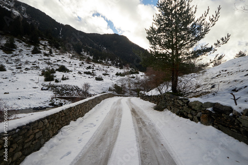 Quadro su tela Carretera de montaña cubierta de nieve con huellas recientes, flanqueada por mur