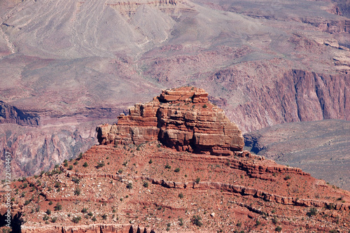 Panoramic view of the Grand Canyon with layered red rock formations, steep cliffs, and wide valleys beneath a clear blue desert sky