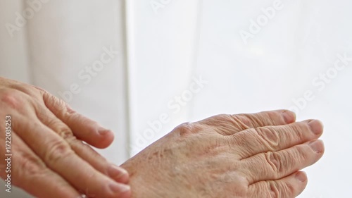 Aged hands, close-up shot of an elderly woman’s, applies a moisturizing cream, massaging it into her skin to hydrate and nourish. Vitamin mature age creme protection against dryness and wrinkles