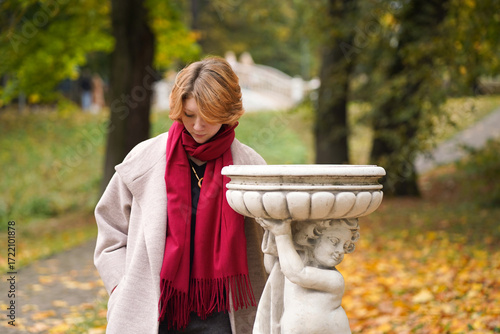 Portrait of a Girl in an Autumn Park in Coat and Red Scarf
