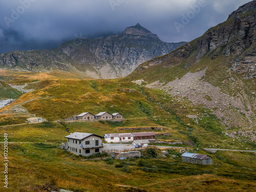 Houses and mountains under cloudy sky in the mountains, Italy.