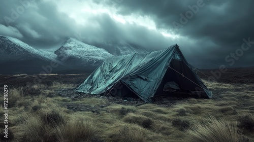 Weathered tent in dramatic mountain landscape stormy sky