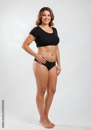 Full-body photorealistic image of a confident British woman after tummy tuck and VASER liposuction, wearing black t-shirt and shorts in a clean white studio setting