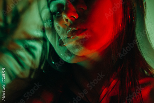 Dreamy portrait of a brunette with bright red flowers in a red green glow with a triple lens and long exposure