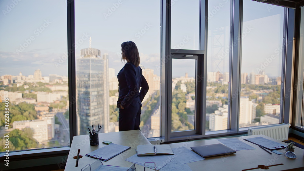 Fototapeta premium Woman executive standing window office highrise building. Elegant businesswoman 