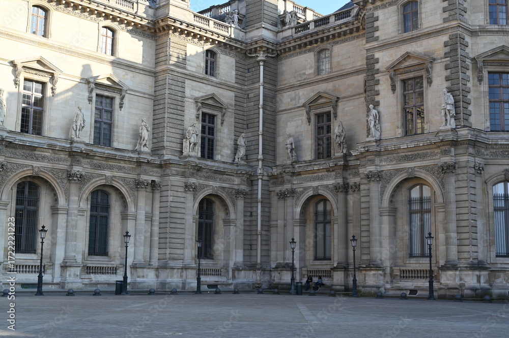 Fototapeta premium Historic European building with stone arches, columns, and ornate architectural details. Classic facade illuminated by daylight, representing traditional urban architecture.
