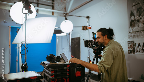 Director of photography with a camera in his hands on the set. Professional videographer at work on filming a movie, commercial or TV series. Filming process indoors, studio