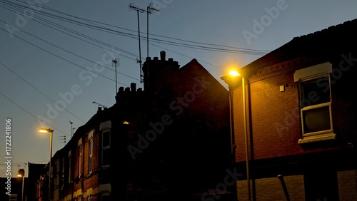 Obraz na plátně A row of British terraced houses silhouetted against a dark evening sky, with st