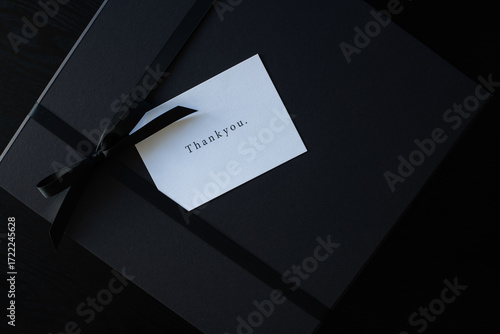 thank you card on a black gift box, tied with a ribbon