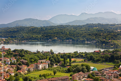 Aerial view of Avigliana lake, Italy, Piedmont, Turin, Italy A beautiful town with and red-roofed houses, surrounded by the green hills of Susa and trees.italian lakes