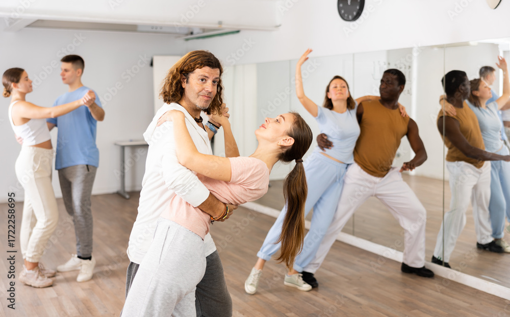 Fototapeta premium Woman and man practicing social dance moves in pair during group class