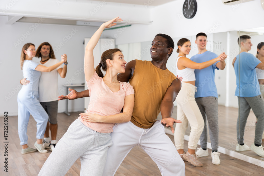 Naklejka premium Woman and man practicing bachata dance moves in pair during group class