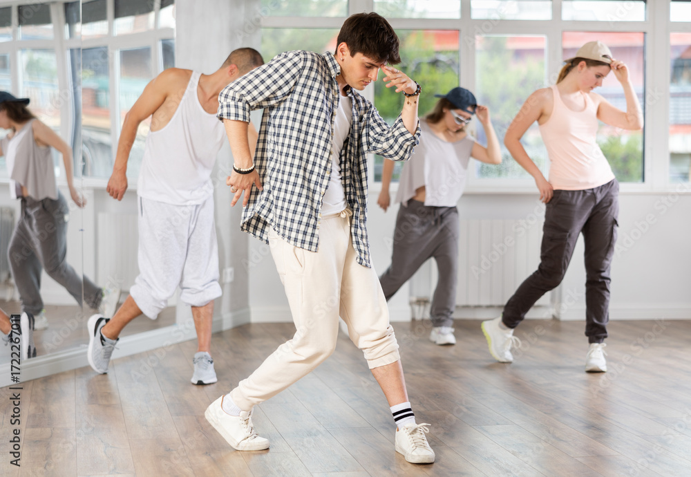 Obraz premium Stylishly dressed young people learn to dance hip-hop and breakdance in a dance studio