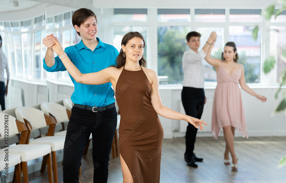 Naklejka premium Young people dancing paired slow waltz dance in a choreographic studio